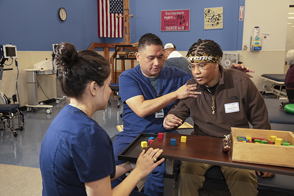 A patient works with blocks with the help of therapists.